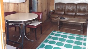 Interior acogedor de una cabaña con comedor, sofá y alfombra estampada.