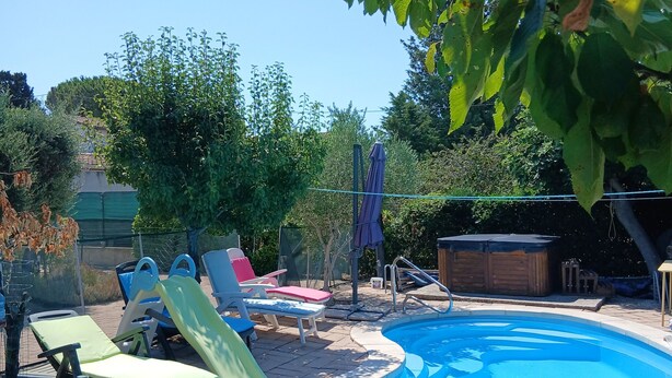 Una piscina con tobogán, rodeada de sillas reclinables y una terraza de madera.