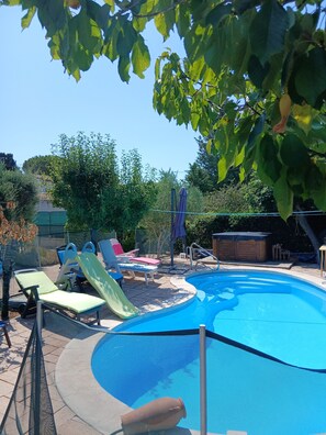 Una piscina con tobogán, rodeada de sillas reclinables y una terraza de madera.