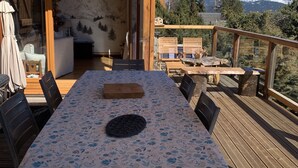 An outdoor dining area with a table covered in a floral tablecloth, surrounded by wooden chairs. - 4 **** CHALET WITH TOURISM CLASSIFICATION  (Les Angles)