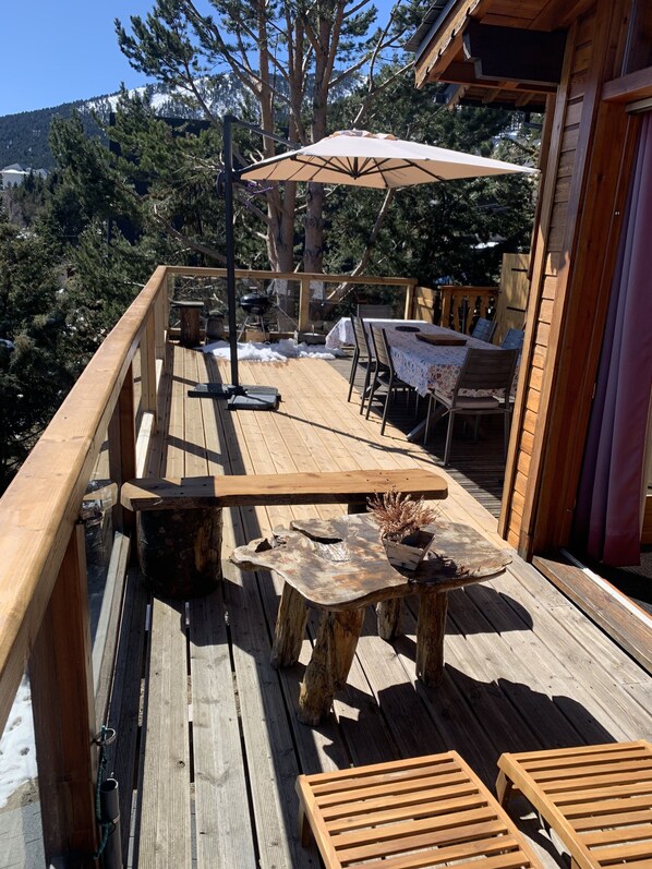 A wooden deck with outdoor furniture, including a table and chairs, and a barbecue grill. - 4 **** CHALET WITH TOURISM CLASSIFICATION (Les Angles)