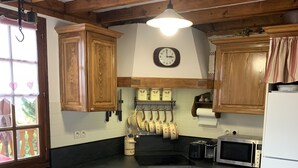 A kitchen with wooden cabinets, a stove, a microwave, and a clock on the wall. - 4 **** CHALET WITH TOURISM CLASSIFICATION  (Les Angles)