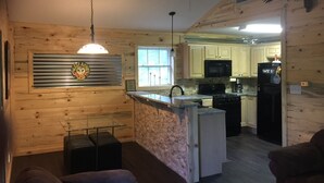 Un acogedor interior de cabaña con cocina, comedor y ventilador de techo.