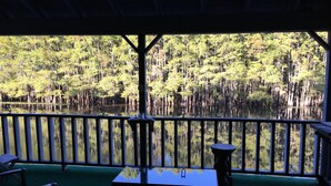 Una terraza con mesa y sillas que da a un lago rodeado de bosque.