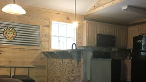 Una sala de estar acogedora con chimenea, un comedor y una cocina con armarios de madera y un refrigerador.