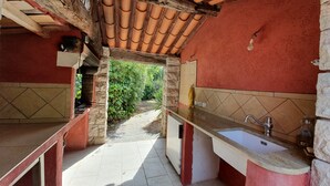 Une cuisine de taille réduite avec un mur en pierre, un pare-feu en carrelage et un plafond en bois.