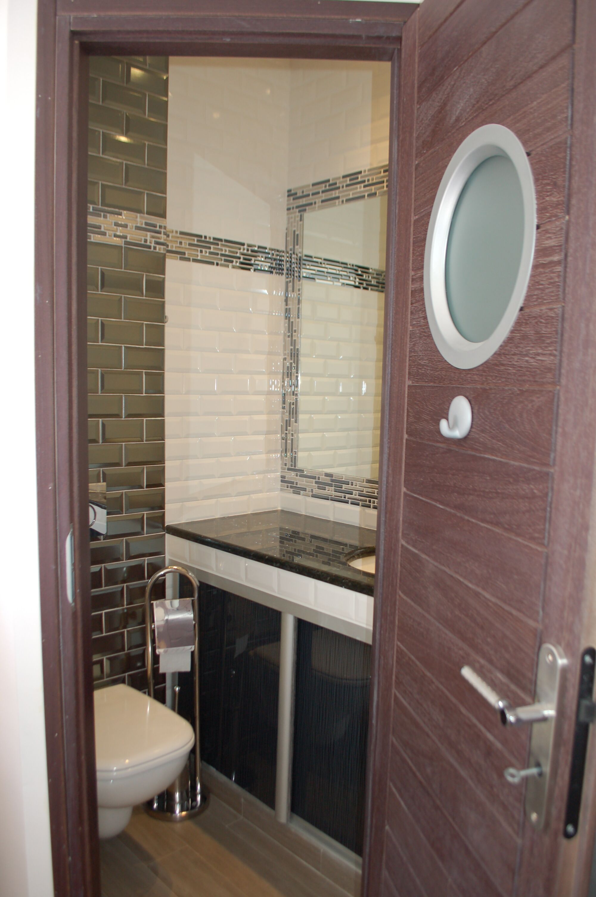 A bathroom with a toilet, sink, and mirror.