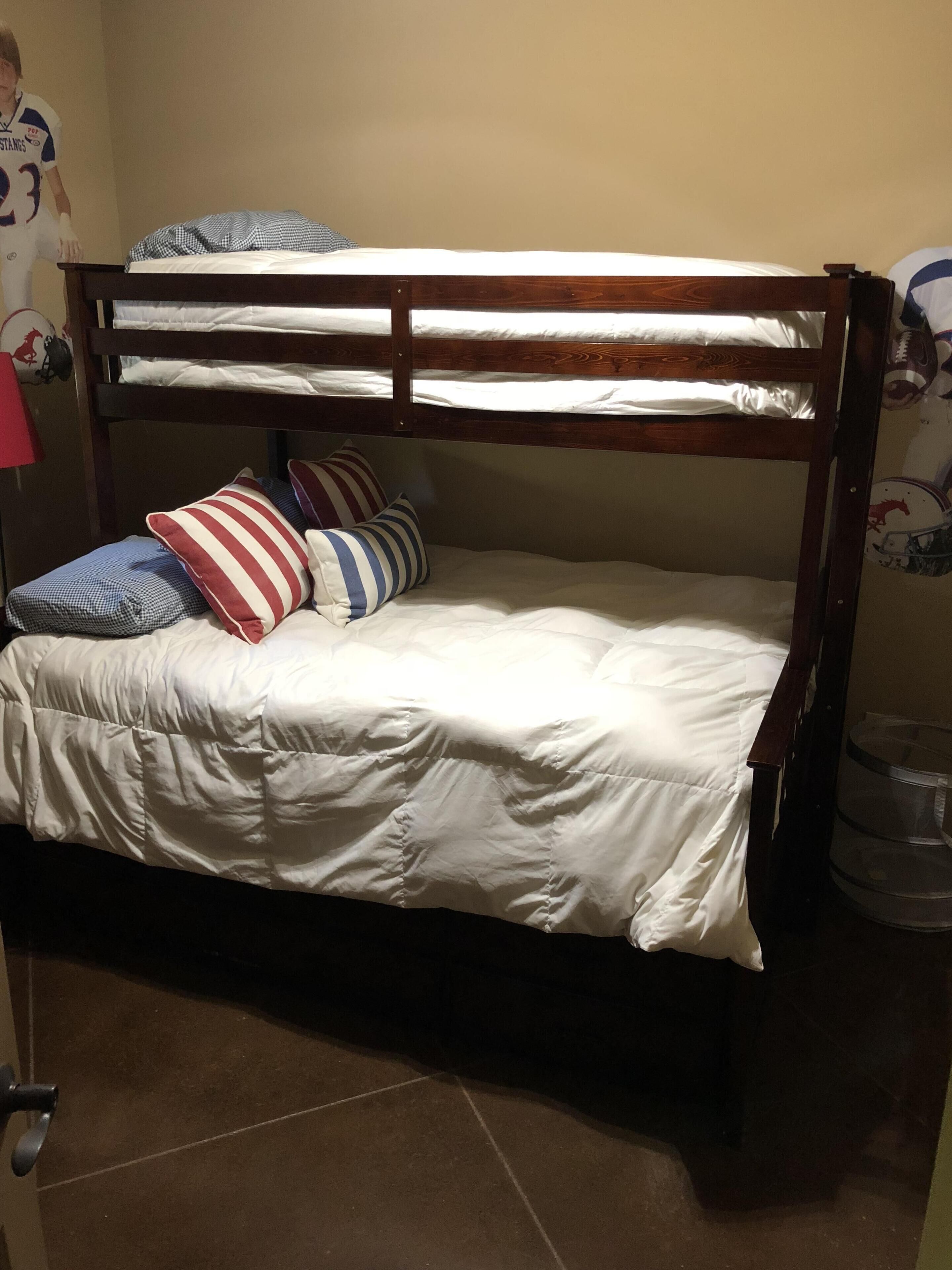 Een stapelbed met witte beddengoed en gestreepte kussens.