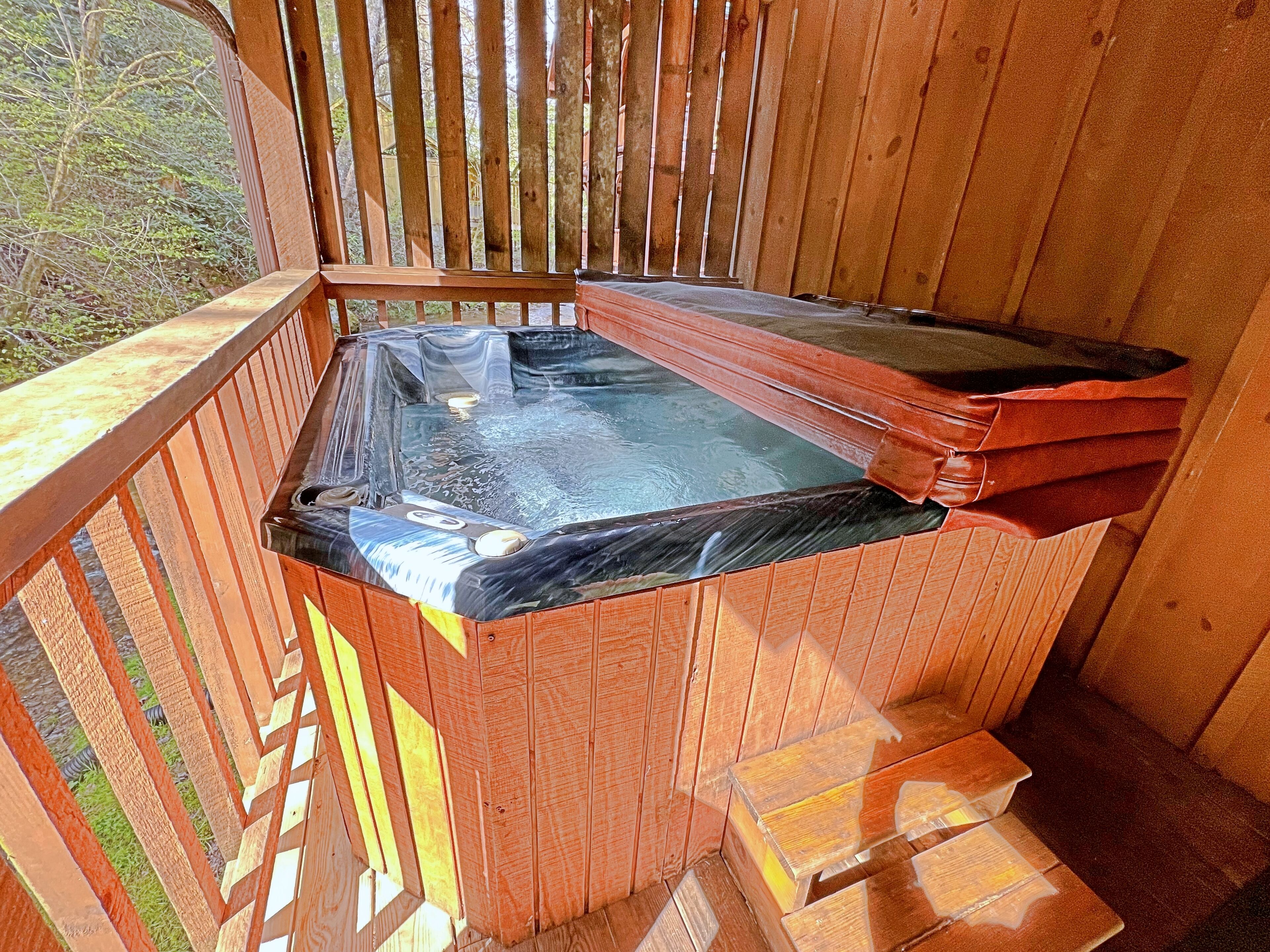Ein hölzernes Whirlpool mit transparentem Deckel, umgeben von Holz-Geländern.