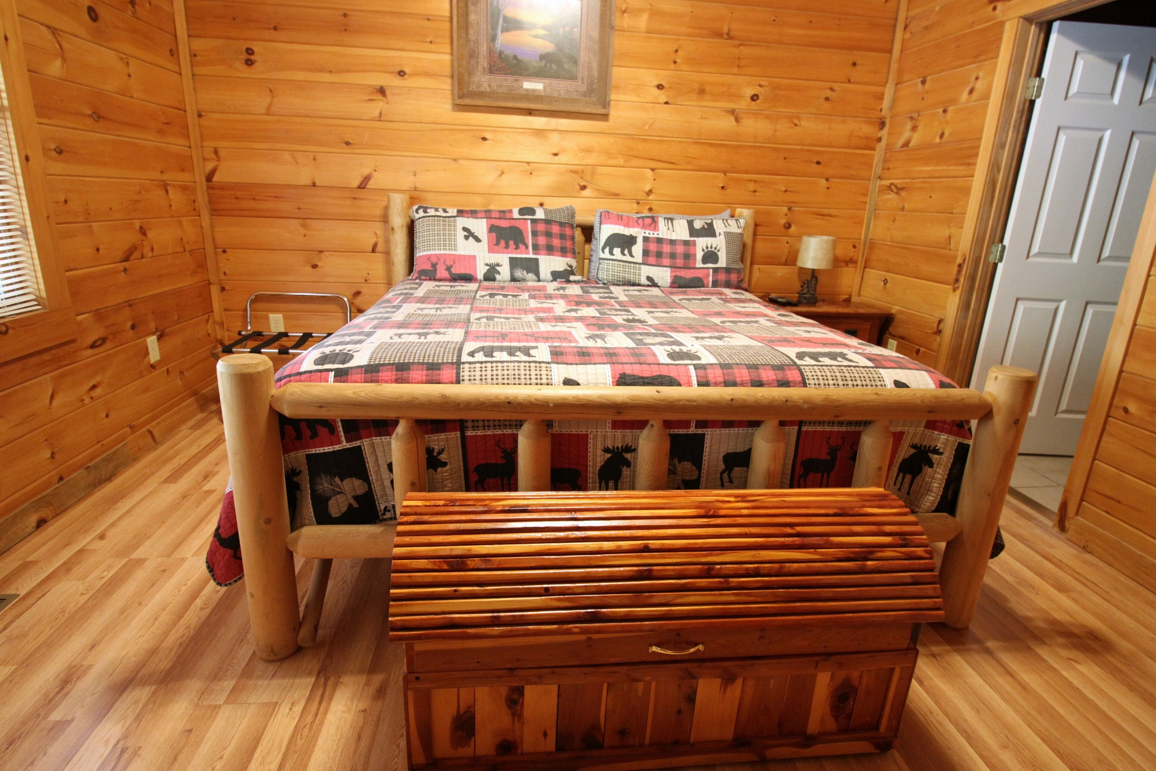 A wooden cabin bedroom with a bed, a bench, and a wooden chest.