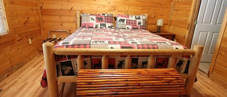 A wooden cabin bedroom with a bed, a bench, and a wooden chest.