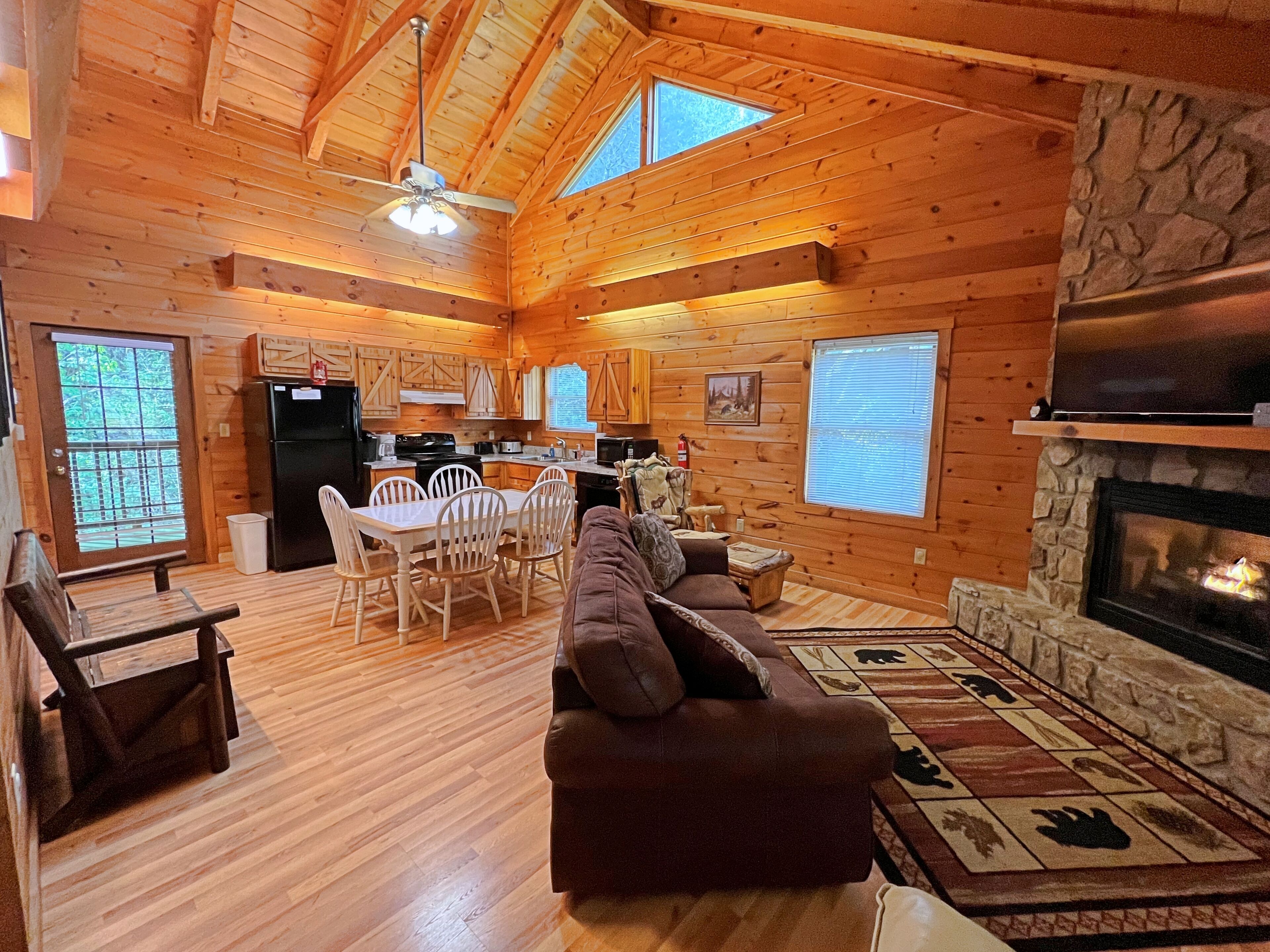 A log cabin with a dining area, living room with a fireplace, and a kitchen.