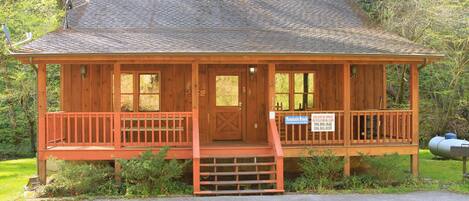 A wooden cabin with a porch, a door, and a sign indicating it is for rent.