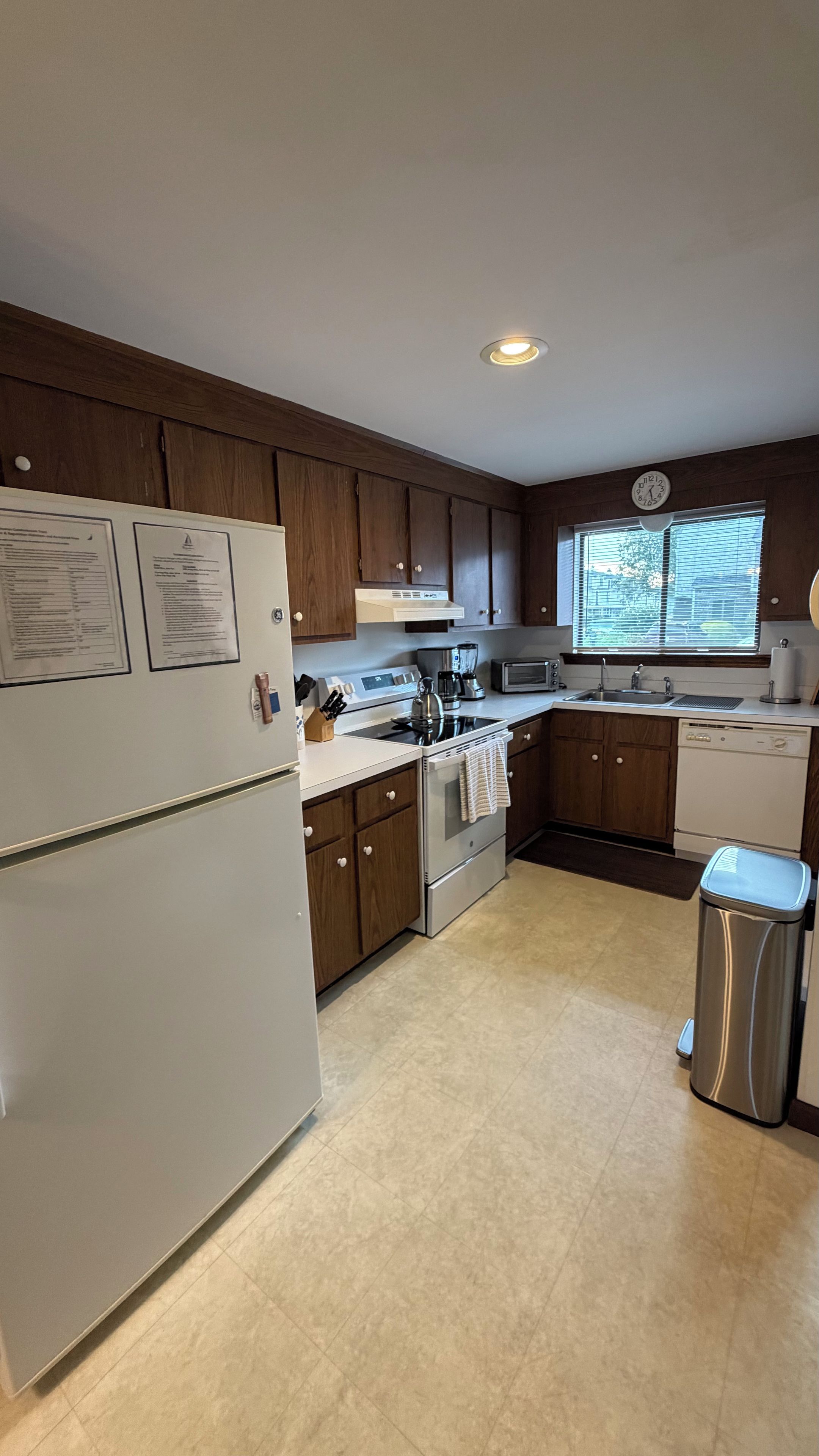 A modern kitchen with wooden cabinets, a stainless steel refrigerator, a stove, a microwave, and a dishwasher.