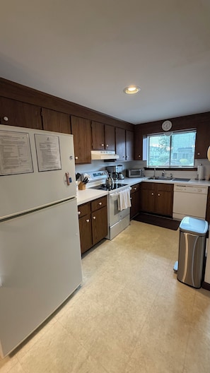 A modern kitchen with wooden cabinets, a stainless steel refrigerator, a stove, a microwave, and a dishwasher.