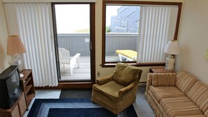 Ein Wohnzimmer mit einer Couch, einem Sessel und einem Fernseher auf einem Holzboden.