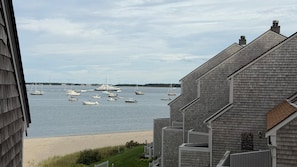 A view of a marina with boats docked, a sandy beach, and a building with a sloped roof.