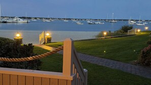 A waterfront property with a grassy lawn, a wooden deck, and a view of boats on the water.