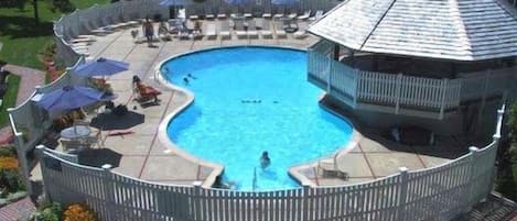 A round swimming pool with a wooden deck and a gazebo-like structure.