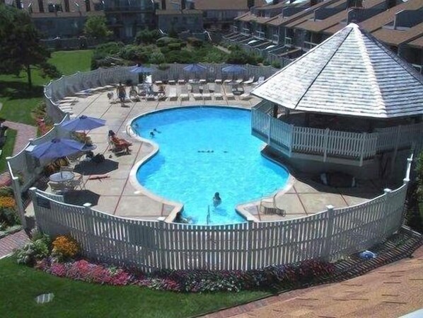 A round swimming pool with a wooden deck and a gazebo-like structure.