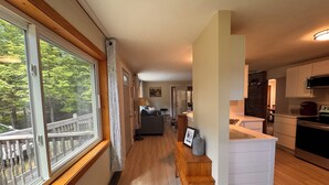 A modern kitchen with a built-in oven and microwave, a wooden dining table with chairs, and a view of the outdoors through large windows.