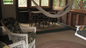 A room with wicker furniture, a hammock, and a view through lattice windows.