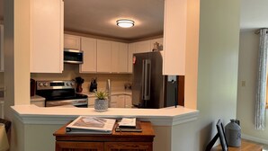 A modern kitchen with white cabinets, stainless steel appliances, and a wooden island with a plant.
