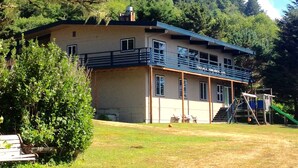 Un edificio di due piani con un balcone, circondato da alberi e da una zona verde.