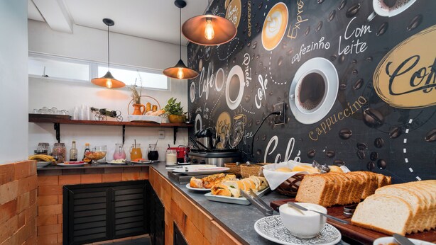 A café counter with coffee cups, pastries, and bread. - Hotel Conchas (Penha)