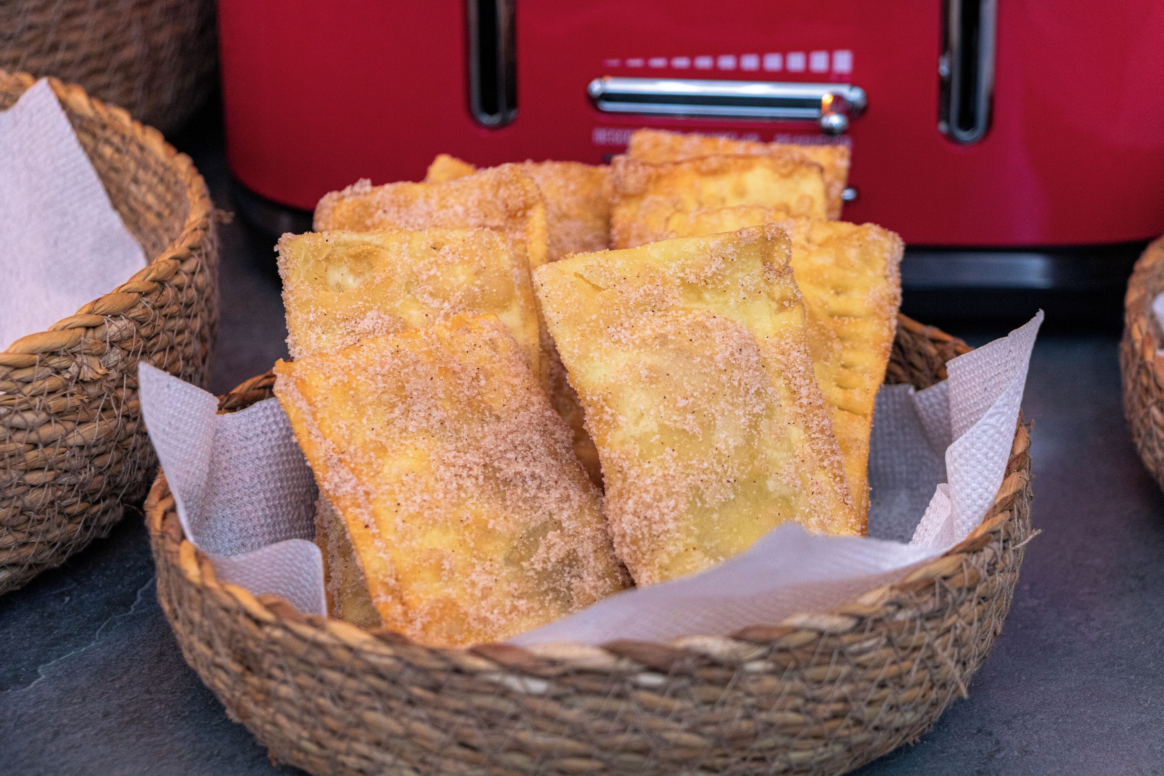 Uma cesta com vários petiscos empanados e fritos, dentro de uma cesta de palha.