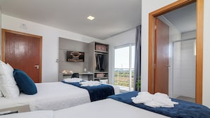 A hotel room with two beds, a desk, a wardrobe, and a balcony with a view. - Hotel Conchas (Penha)