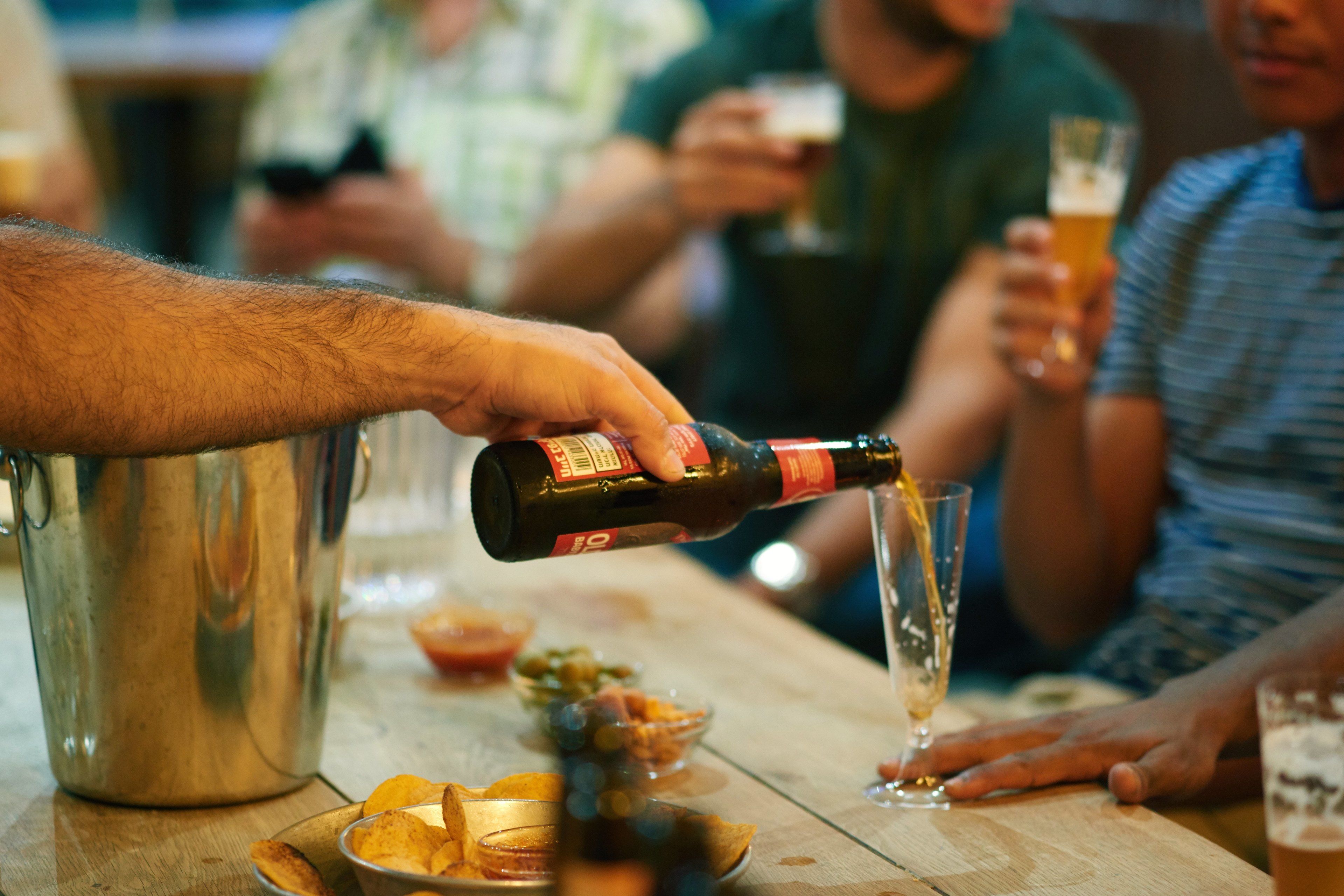 A person pouring a drink from a bottle into a glass.