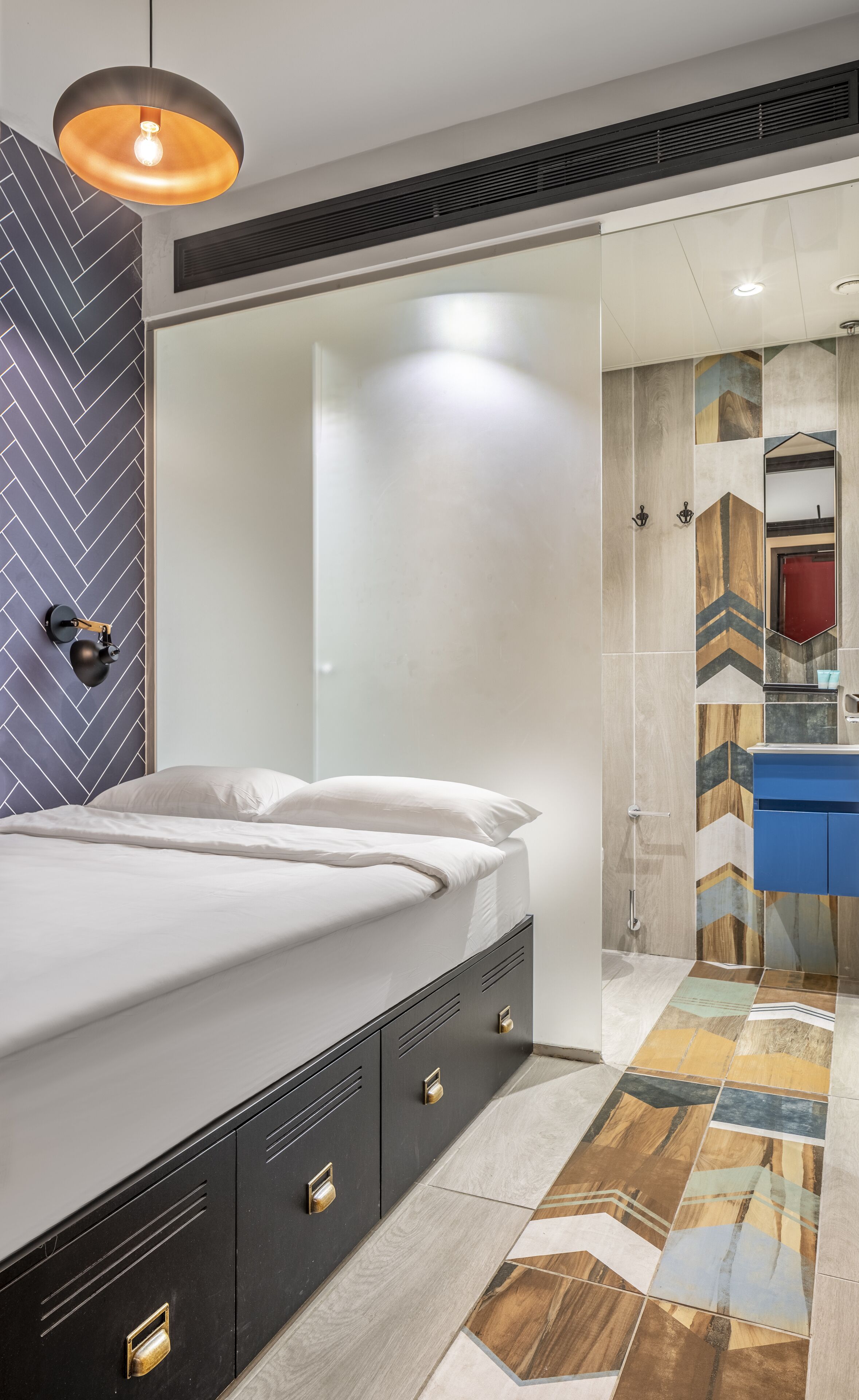 Een moderne slaapkamer met een bed, nachtkastjes en een badkamer met een spiegel en wastafel.