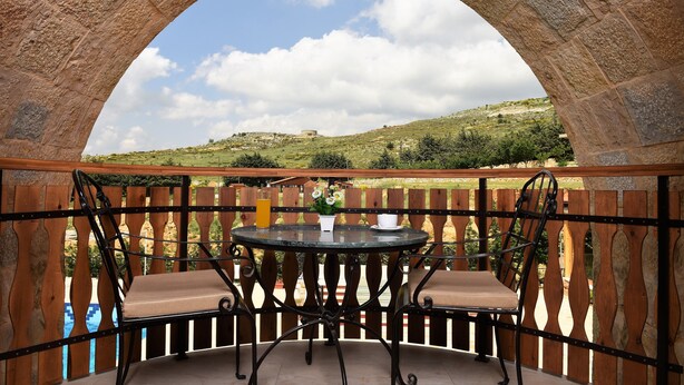 An outdoor seating area with a stone arch, a round table, and two chairs. - Palais Des Cedres (Barouk)