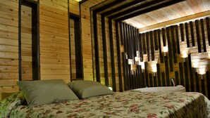 A wooden cabin-style room with a bed, pillows, and a wall-mounted light fixture. - Palais Des Cedres (Barouk)