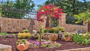 Un jardin aménagé avec une grande variété de plantes et de fleurs, un mur en pierre et une clôture en métal.