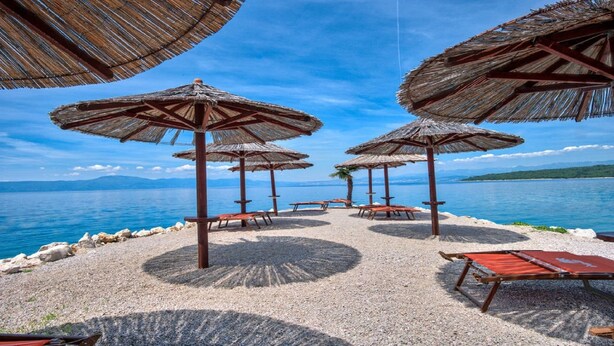 Une plage avec des parasols en chaume et des bancs en bois.