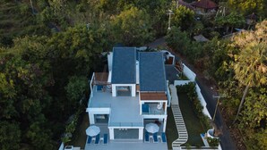 A modern two-story house with a swimming pool, surrounded by dense greenery. - Modern Oceanfront Luxury in the Unspoilt Beauty of the Original Bali (Seririt)