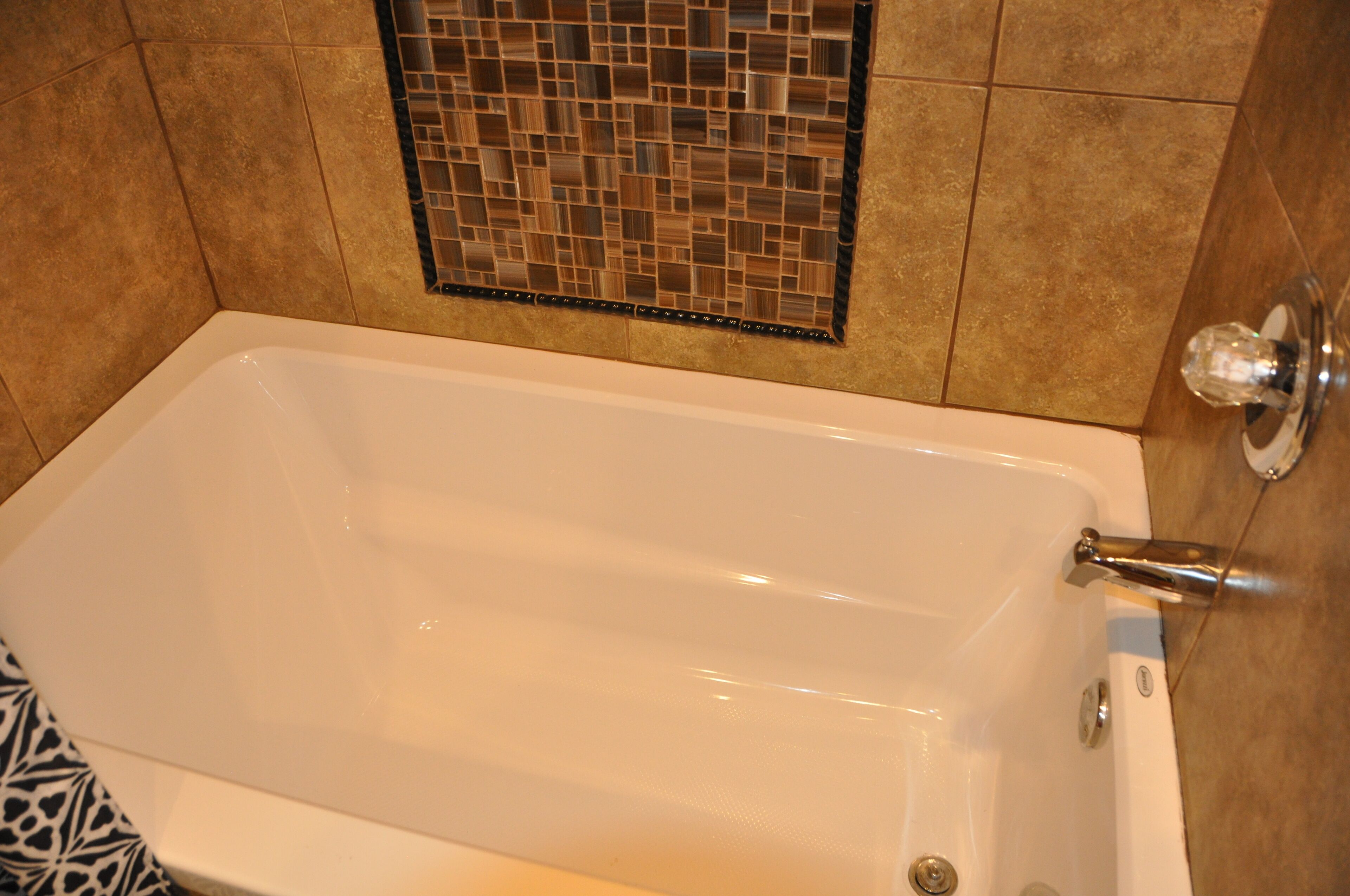 Una bañera con pared de azulejos y ducha.