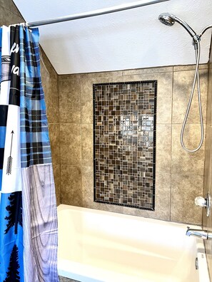 Bañera con ducha, toallas, papel higiénico