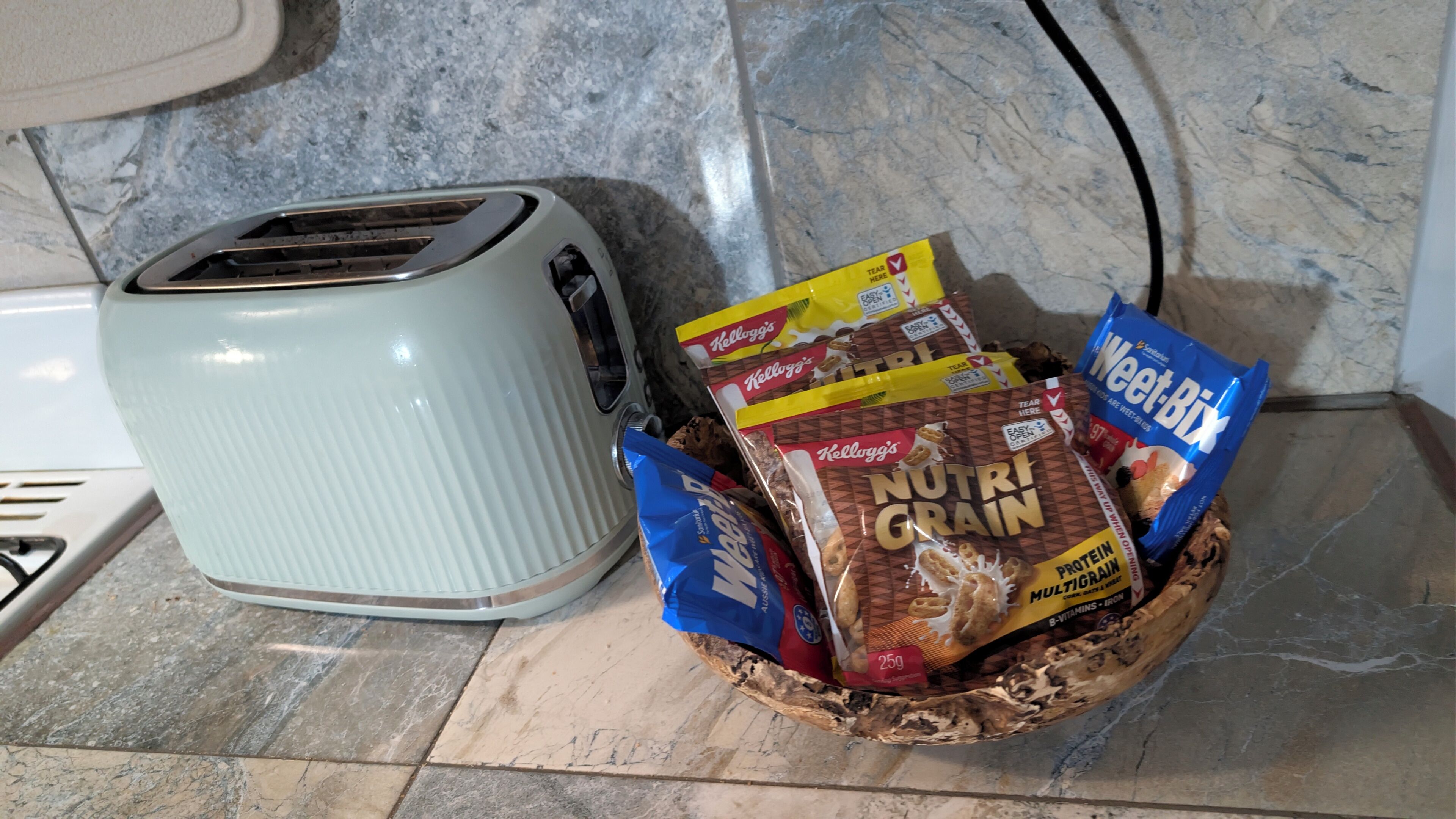 Eine Küchenarbeitsplatte mit einem Toaster und einer Schüssel voller verpackter Lebensmittel.