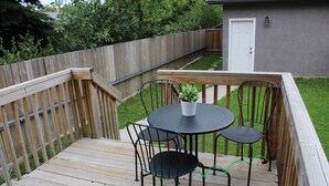 A wooden deck with a round table and four chairs, a potted plant, and a white door in the background. - Modern 2 BD RM Vacation Home Near West Edmonton Mall & Transit Center/LRT (Edmonton)