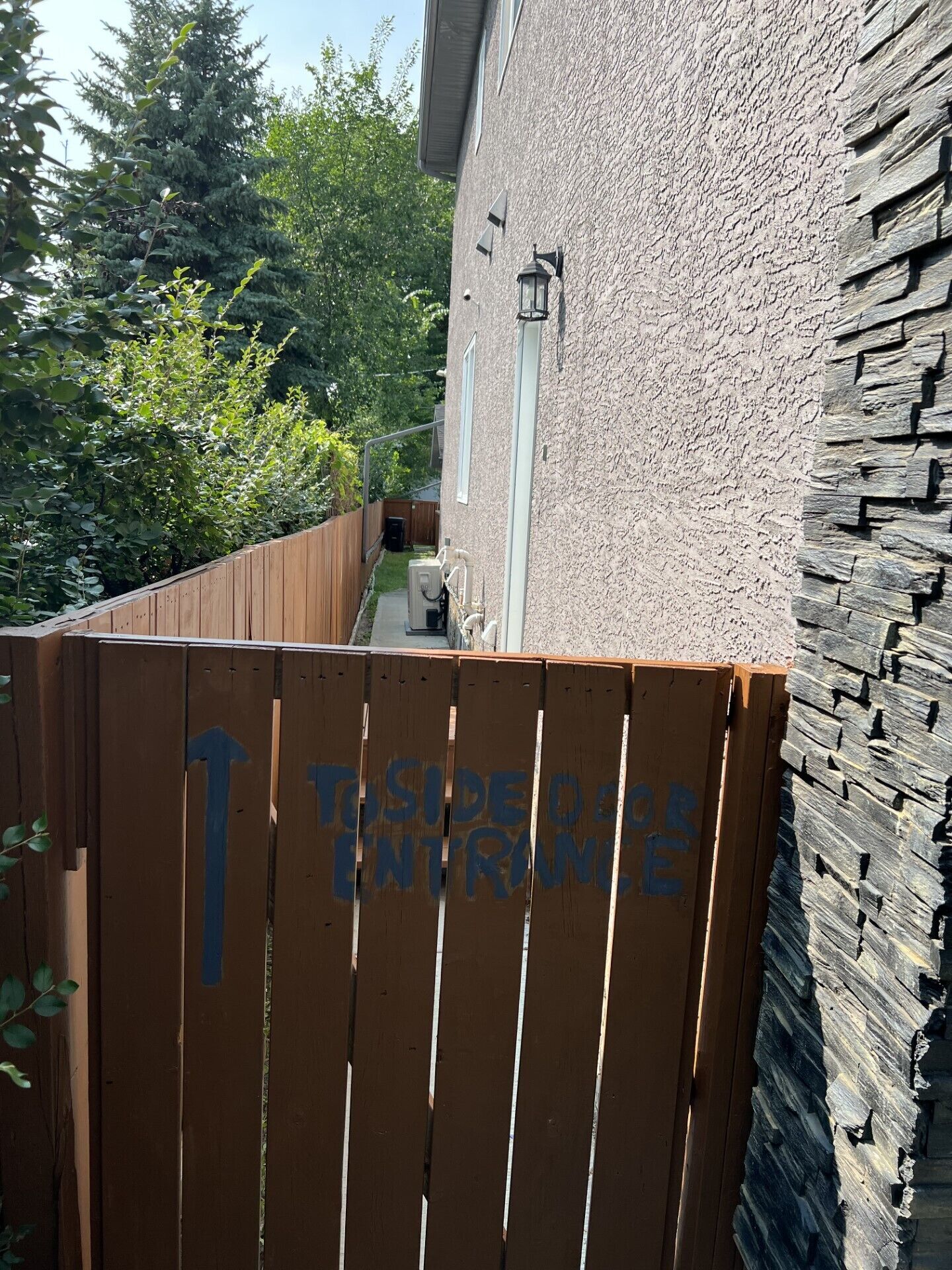 Una puerta de madera con una flecha azul que apunta hacia arriba y el texto 'TO SIDE OF ENTRY' pintado en ella.