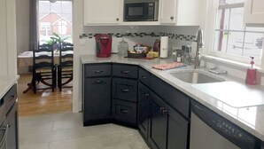 A modern kitchen with black cabinets, a microwave, and a sink.