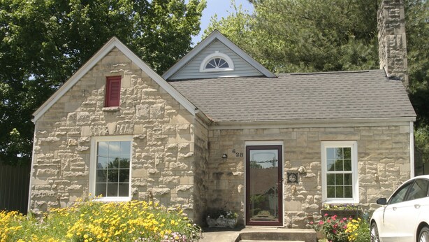 A stone house with a gabled roof, a front door, and a small porch.