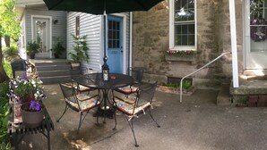 A patio with a round table and four chairs, a blue door, and stone walls.