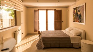 A bedroom with a bed, a bedside table, a nightstand, a window, and a painting on the wall. - Villa immersed in the Green (Pellaro)