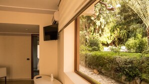A bathroom with a sink, a mirror, and a TV mounted on the wall. - Villa immersed in the Green (Pellaro)