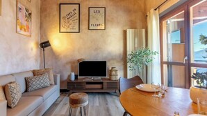 A living room with a sofa, a TV, a dining table with chairs, and framed artwork on the wall. - THE LOFT by Design Studio (Bellano)