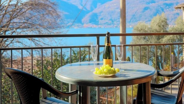 A round table with a bottle and glasses, a plate of grapes, and a view of mountains. - THE LOFT by Design Studio (Bellano)
